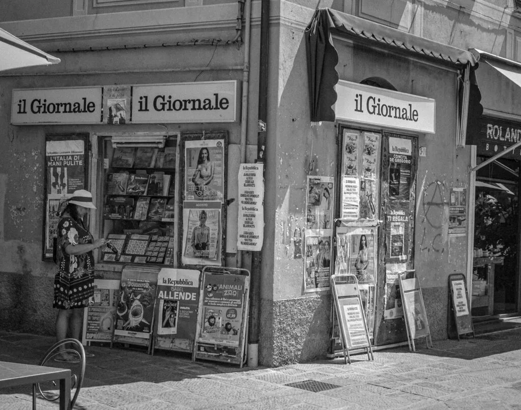 Black and white photo of an Italian street newspaper stand.